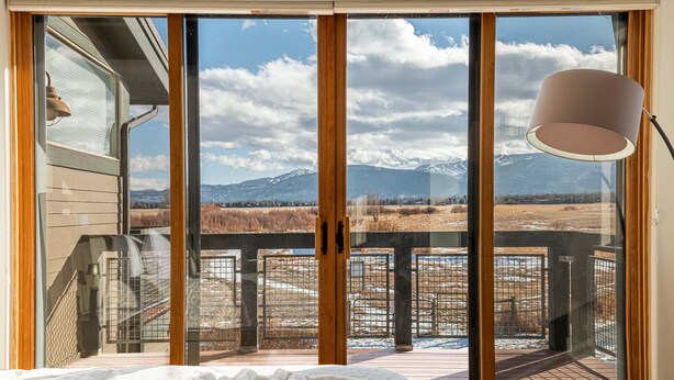 Une chambre dotée d’une grande porte-fenêtre coulissante donnant sur une terrasse avec vue sur les montagnes.
