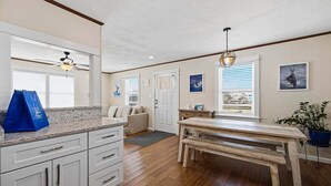 A kitchen with a wooden table, white cabinets, and a ceiling fan.