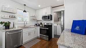 A modern kitchen with white cabinetry, stainless steel appliances, and granite countertops.