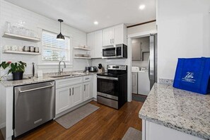 A modern kitchen with white cabinetry, stainless steel appliances, and granite countertops. - Billfish Bungalow | 1950 ft to the beach | Dog Friendly and Hot Tub (Nags Head)