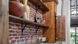 Een keuken met een bakstenen muur, houten planken en een kast.