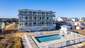 Un hotel de varios pisos con zona de piscina, balcones y vista a la playa.