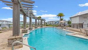Ein Swimmingpool mit einer Holz-Pergola, Liegestühlen und einem Steinrand.