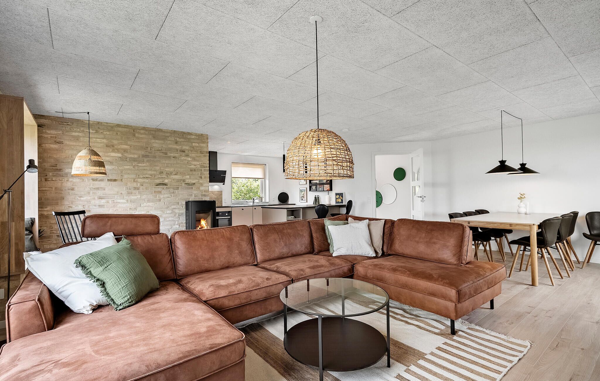 Ein modernes Wohnzimmer mit einer Eckcouch, einem Glastisch und einem Kamin.