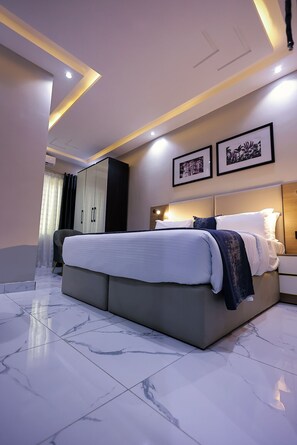 A modern bedroom with a large bed, a wardrobe, and a nightstand. - Ringruby Hotel, Oduduwa Way (Lagos)