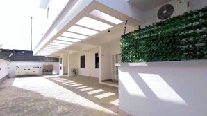 Un espace extérieur abrité doté d’un sol carrelé, d’un mur recouvert de verdure et d’un plafond agrémenté de lucarnes.