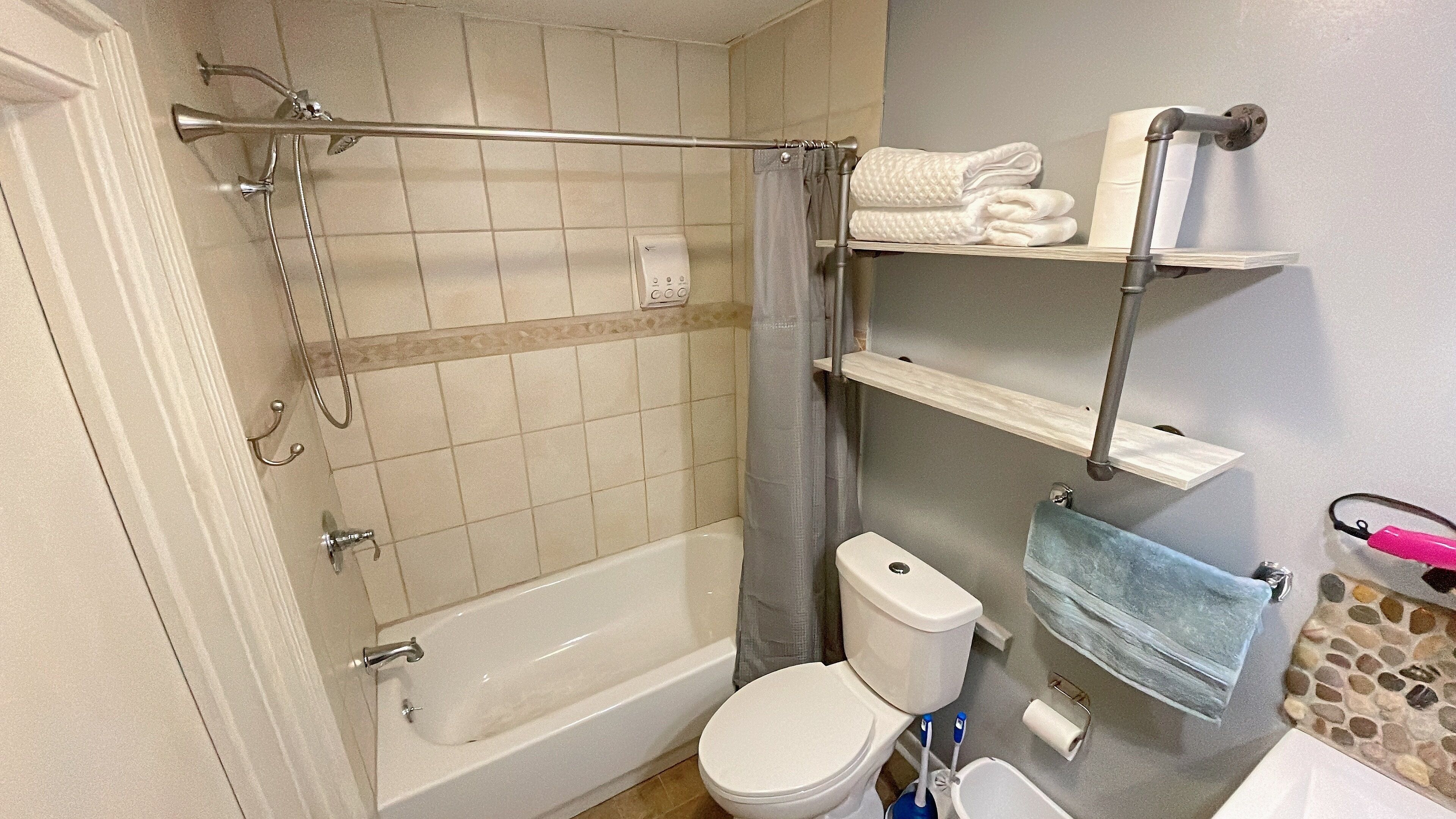 A bathroom with a bathtub, toilet, and a shower area.