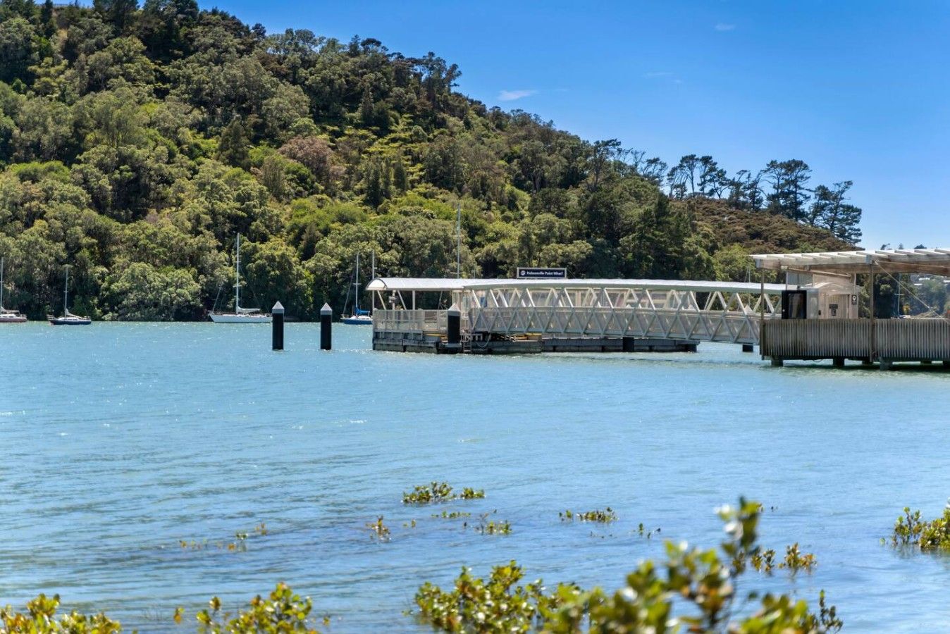 A ferry crossing a calm lake with a forested hillside in the background.