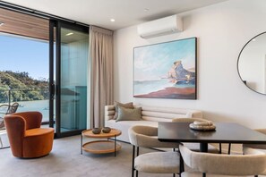 A modern living room with a sofa, chairs, a coffee table, and a painting of a landscape.