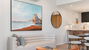 Un salon moderne avec un canapé, une table basse et un tableau représentant une scène de plage.