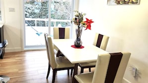 A dining area with a white table, four chairs, and a vase with flowers.