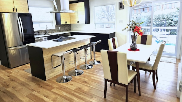 A modern kitchen with a central island, stainless steel appliances, and a dining area with bar stools.