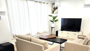 A modern living room with a sofa, a coffee table, and a TV.