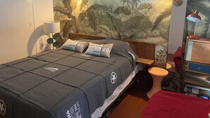 A bedroom with a bed, a nightstand, a lamp, and a wall mural.