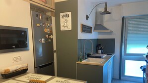 A compact kitchen with a refrigerator, a sink, and a dining area with menu boards.