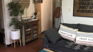 A living room with a sofa, a coffee table, a clock, a plant, a wooden cabinet, and a wall with alphabet letters.