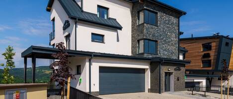 A modern two-story house with a garage, a covered porch, and a stone facade.