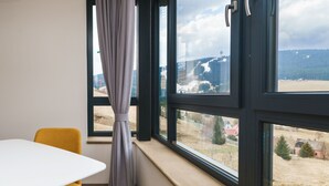 Ein Zimmer mit großem Fenster, einem weißen Tisch und einem gelben Stuhl.