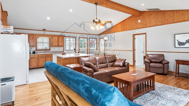 Ein geräumiger Wohnbereich mit einem braunen Ledersofa, einer blauen gepolsterten Bank und einem Holztisch. Im Hintergrund ist ein Holzesstisch mit Stühlen zu sehen.
