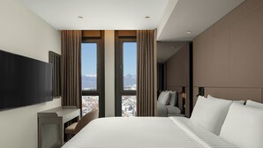 Une chambre d’hôtel moderne avec un grand lit, un bureau et une télévision.