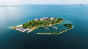 An aerial view of a tropical island with a marina, solar panels, and a variety of buildings. - The Westin Nirup Island Resort & Spa (Nirup Island)