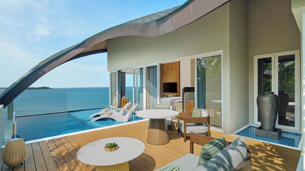 Una terraza moderna al aire libre con piscina, sillones de descanso y zona de comedor con vistas al mar.