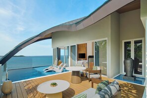 A modern outdoor deck with a pool, lounge chairs, and a dining area overlooking the sea. - The Westin Nirup Island Resort & Spa (Nirup Island)