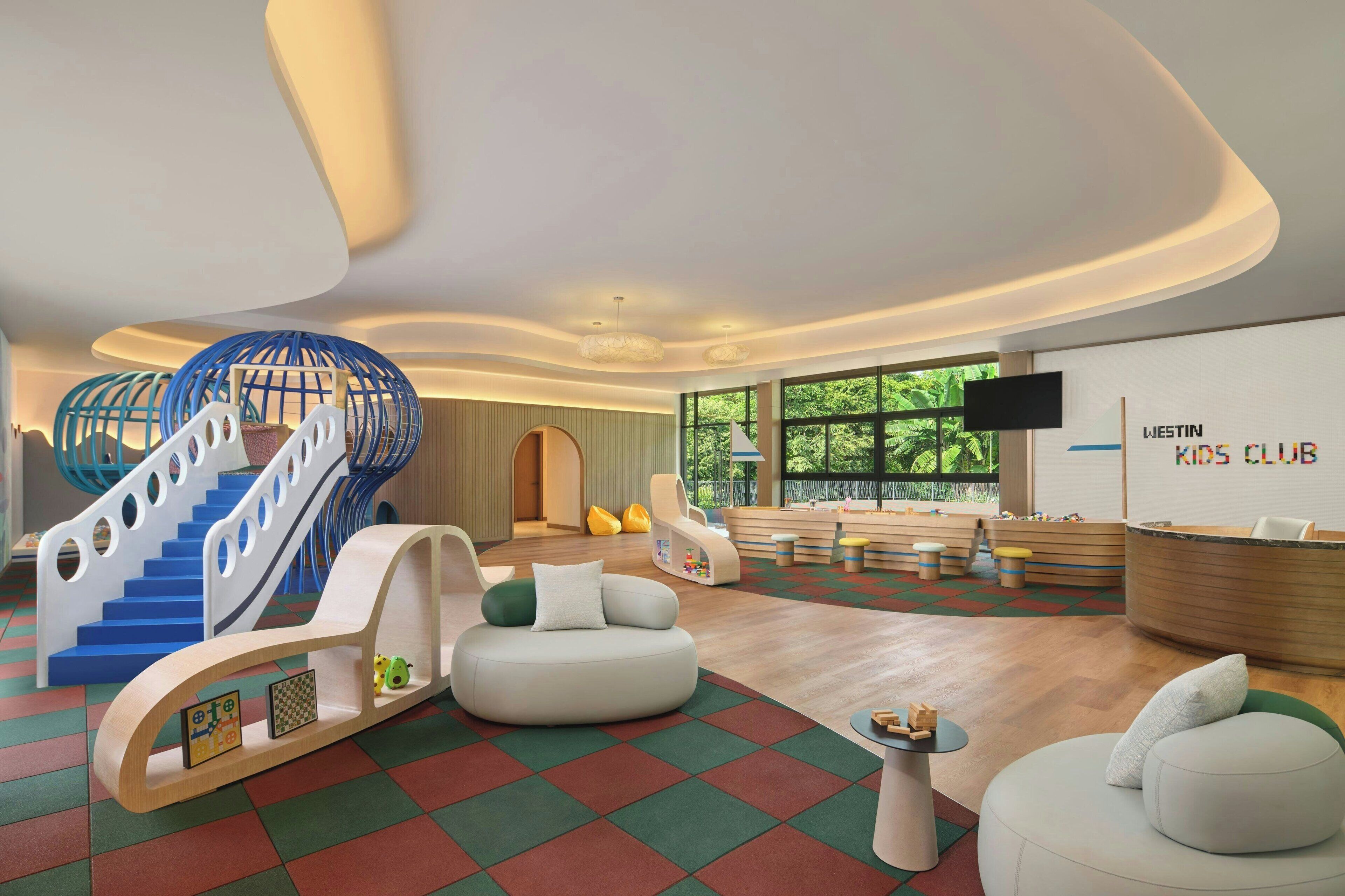 Un club infantil moderno con zona de juegos, asientos y mostrador de recepción.
