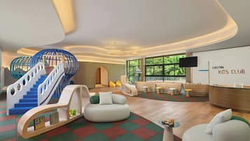 Un club infantil moderno con zona de juegos, asientos y mostrador de recepción.