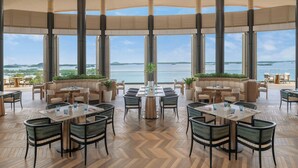 Un amplio comedor interior con techos altos, ventanas grandes y vista al mar.