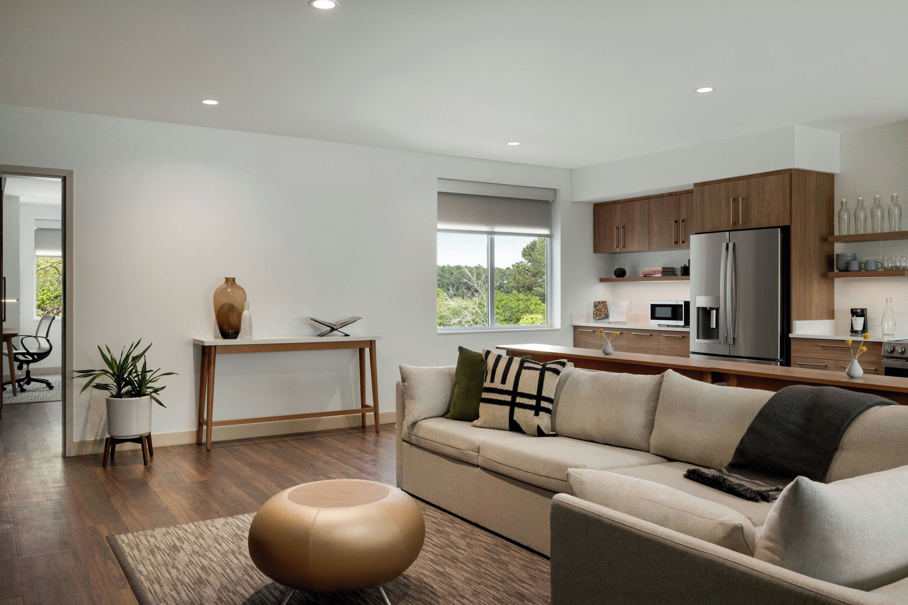 A modern living room with a sofa, coffee table, and a dining area with a table and chairs.