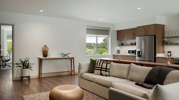 A modern living room with a sofa, coffee table, and a dining area with a table and chairs.