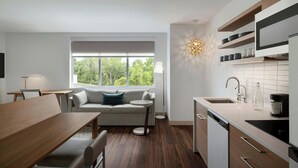 A modern kitchen with a dining area, a sofa, and a large window. - Element by Marriott Charleston Airport (North Charleston)