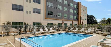 A swimming pool with lounge chairs and a building in the background.