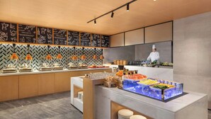A modern buffet setup with a chef preparing food, a chalkboard menu, and a variety of food items displayed. - Fairfield by Marriott Hangzhou Gongshu (Hangzhou)
