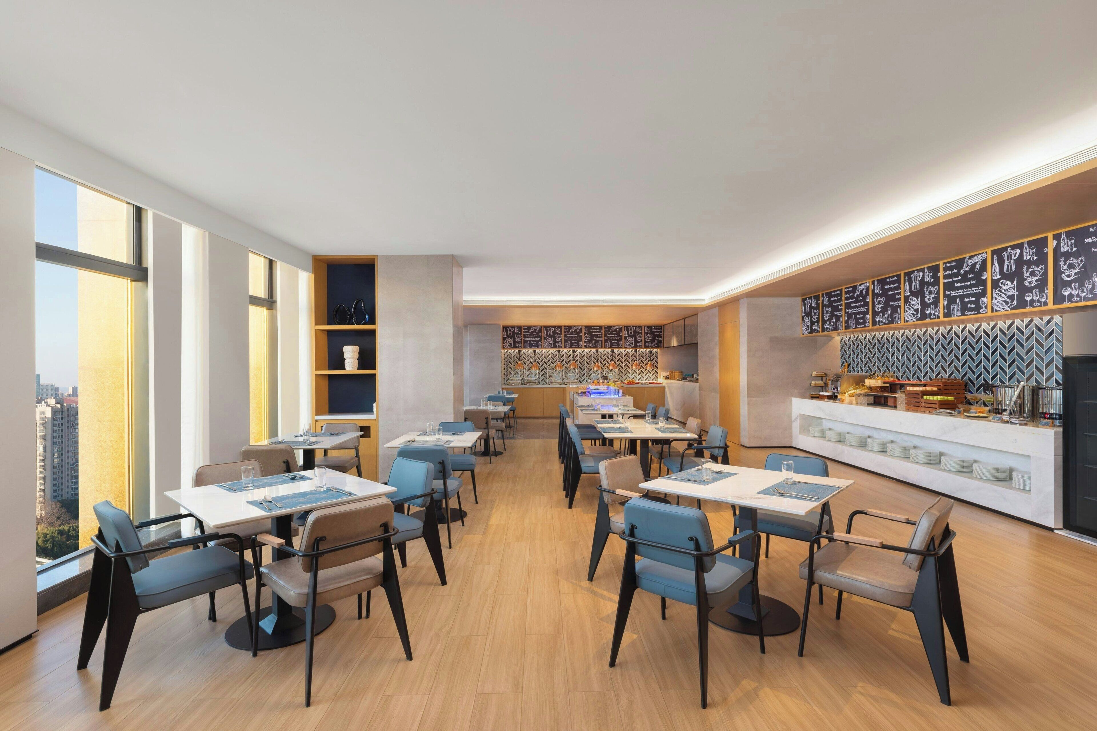 A modern restaurant with high ceilings, large windows, and a variety of seating arrangements.