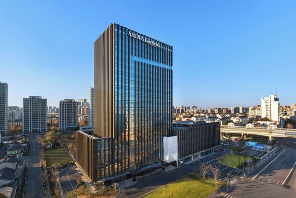 A modern high-rise building with a glass facade and a prominent sign.