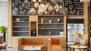 A modern lounge area with a sofa, a coffee machine, and a refrigerator stocked with beverages. - Fairfield by Marriott Hangzhou Gongshu (Hangzhou)