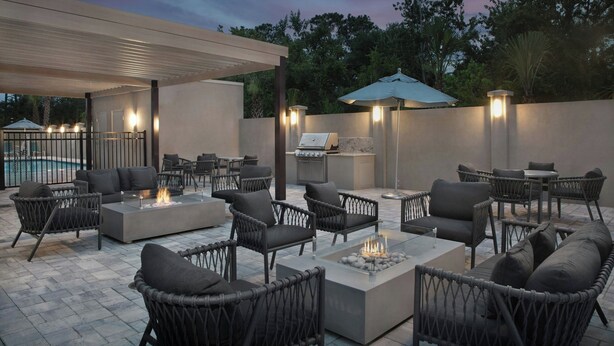 An outdoor patio area with seating, a fire pit, and a barbecue grill. - TownePlace Suites by Marriott® Jacksonville Mayport (Atlantic Beach)