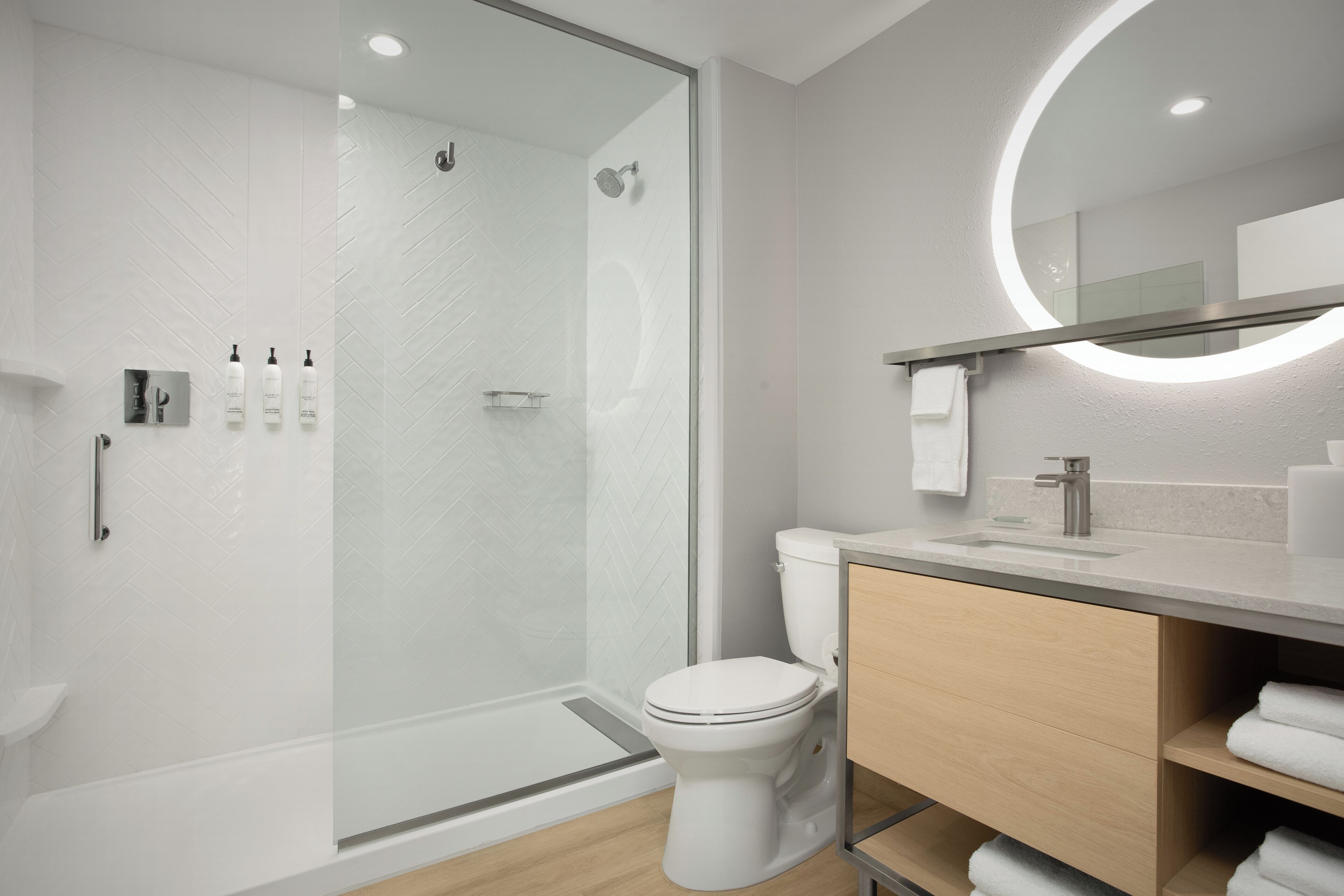 A modern bathroom with a glass-enclosed shower, a toilet, and a vanity with a mirror.