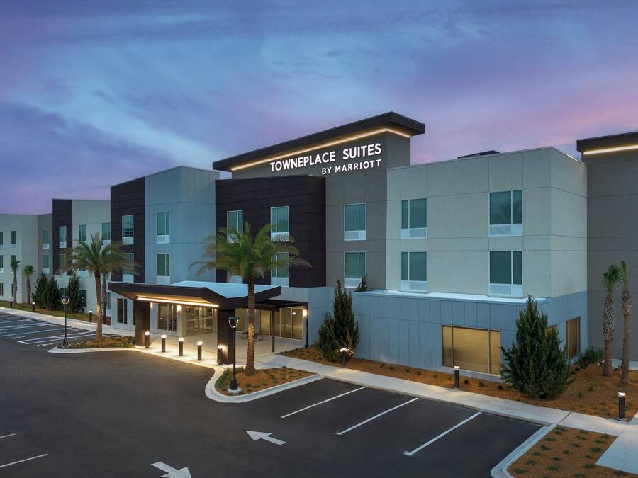 A modern hotel with a sign reading "Towneplace Suites by Marriott" and a parking lot in front.