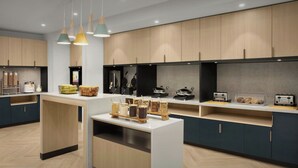 A modern kitchen with wooden cabinets, a central island with jars, and a countertop with toasters. - TownePlace Suites by Marriott® Jacksonville Mayport (Atlantic Beach)
