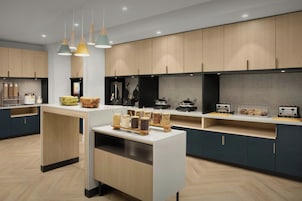 Una cocina moderna con armarios de madera, una isla central con frascos y una encimera con tostadores.