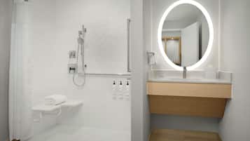 A modern bathroom with a shower, toilet, and vanity with a mirror.