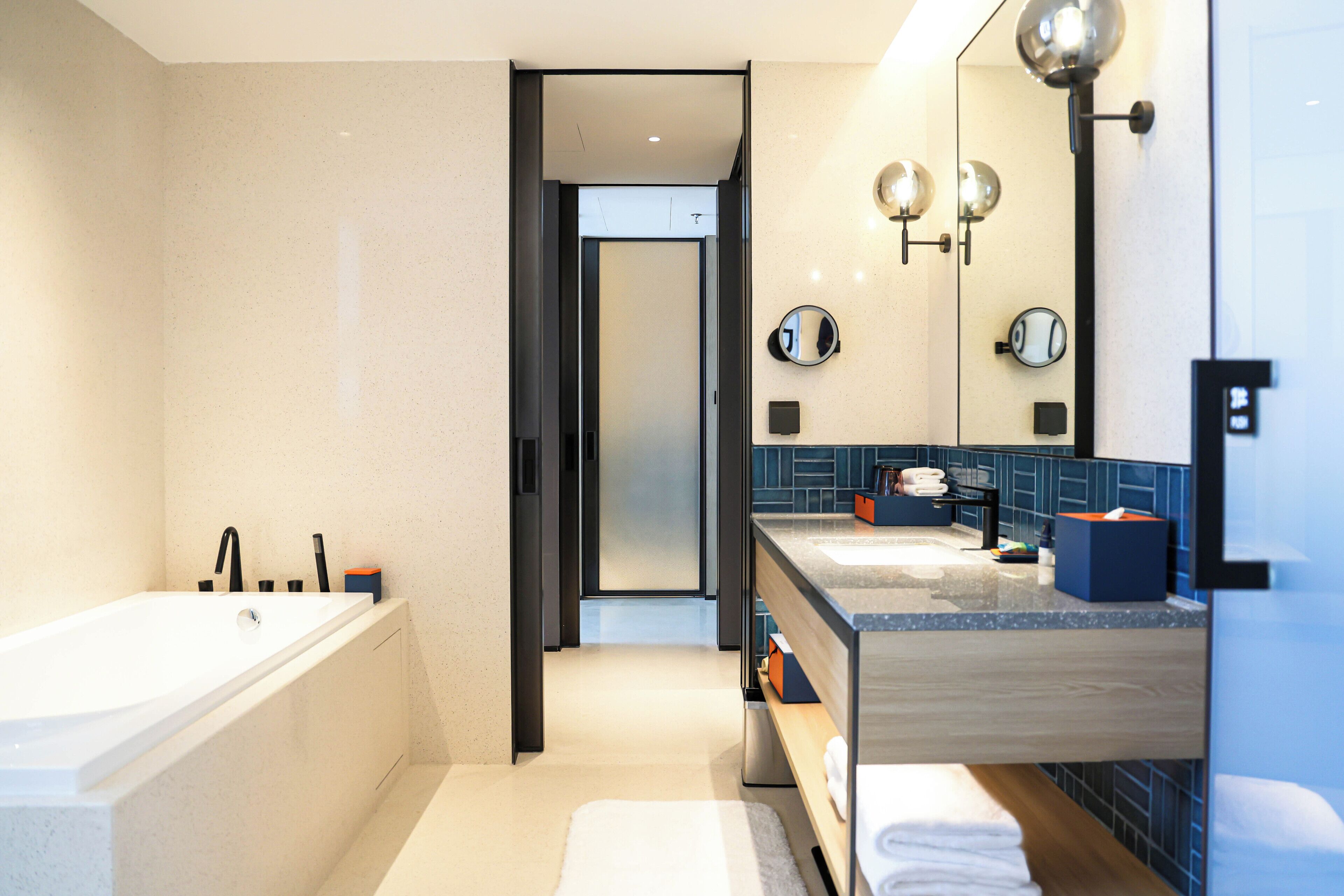 A modern bathroom with a bathtub, a vanity with a mirror, and a shower area.