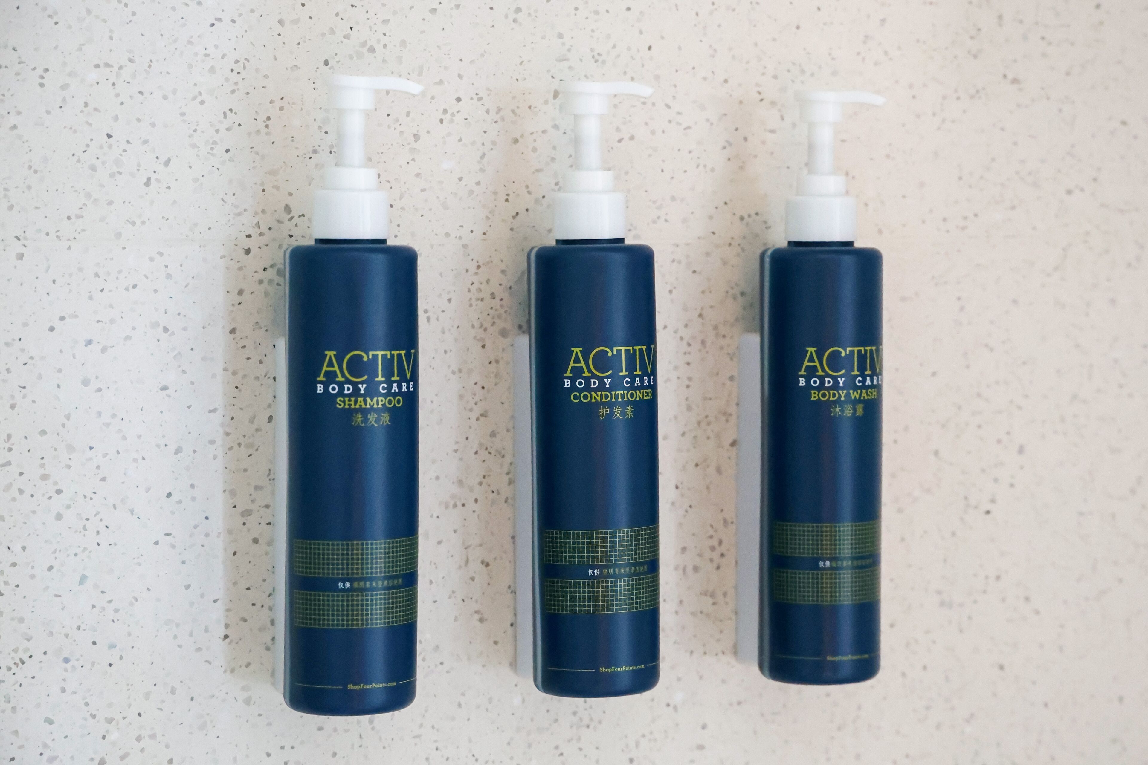 Three bottles of Activ body care products on a speckled surface.