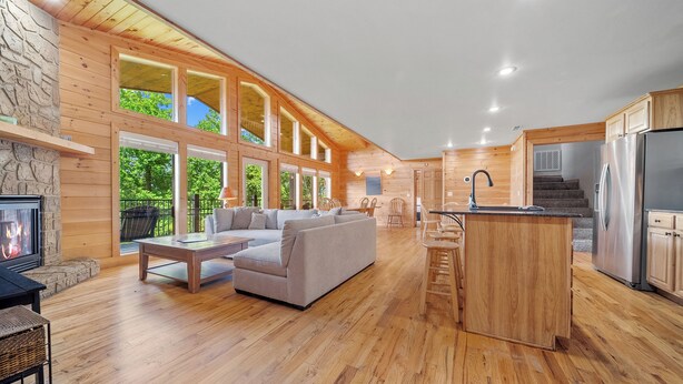 A spacious living area with a fireplace, a sofa, and a wooden dining table. - Smoky Mountains Bliss - Cozy Cabin w/ Amazing Views, Perfect for Big Families!  (Sevierville)