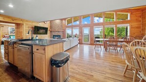 A spacious kitchen with wooden cabinets, a large island, and a dining area with wooden chairs. - Smoky Mountains Bliss - Cozy Cabin w/ Amazing Views, Perfect for Big Families!  (Sevierville)