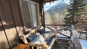 A wooden deck with a rustic sofa and a small table.