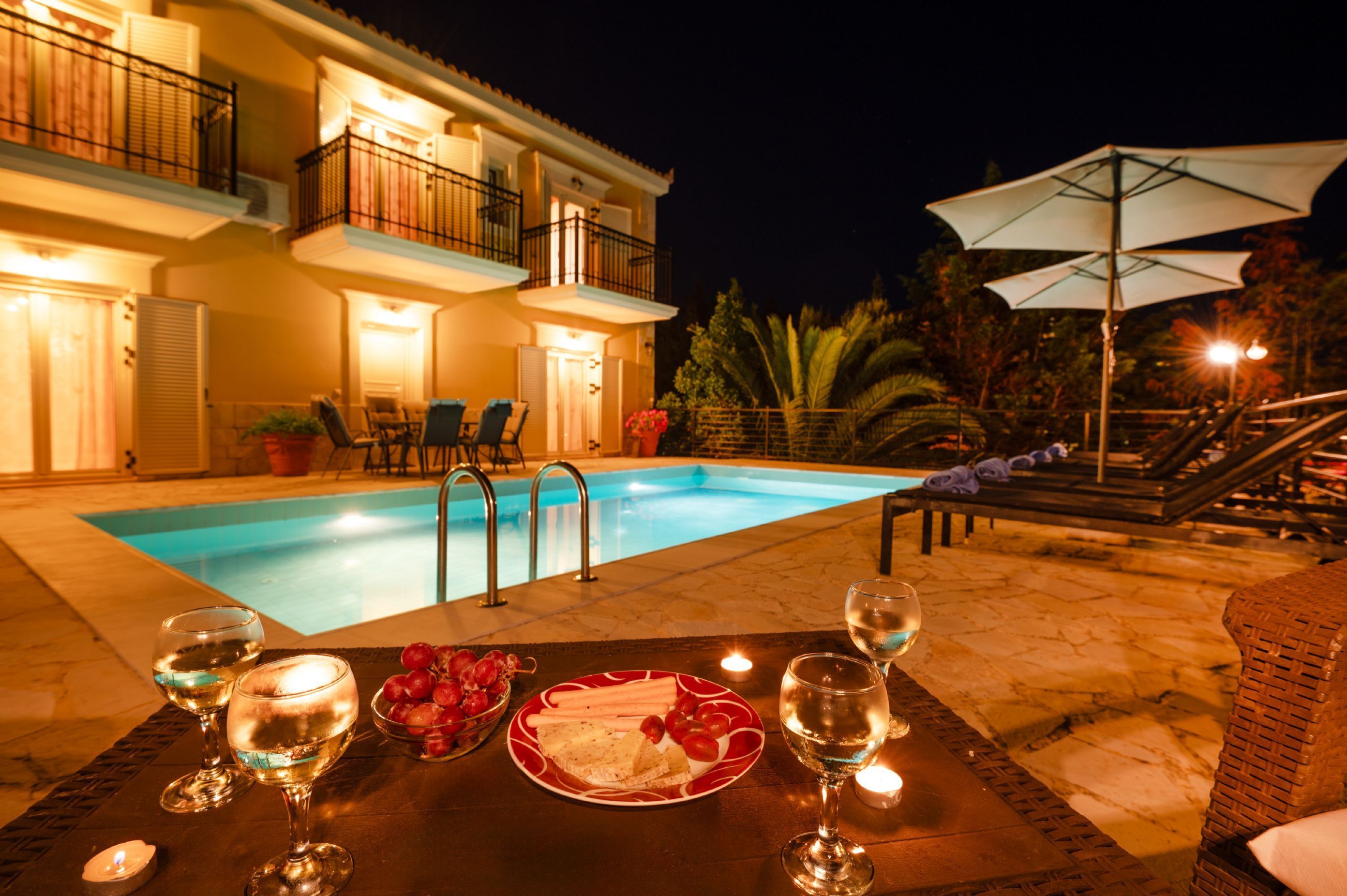 A poolside dining area with a table set for two, a pool, and a building with balconies.